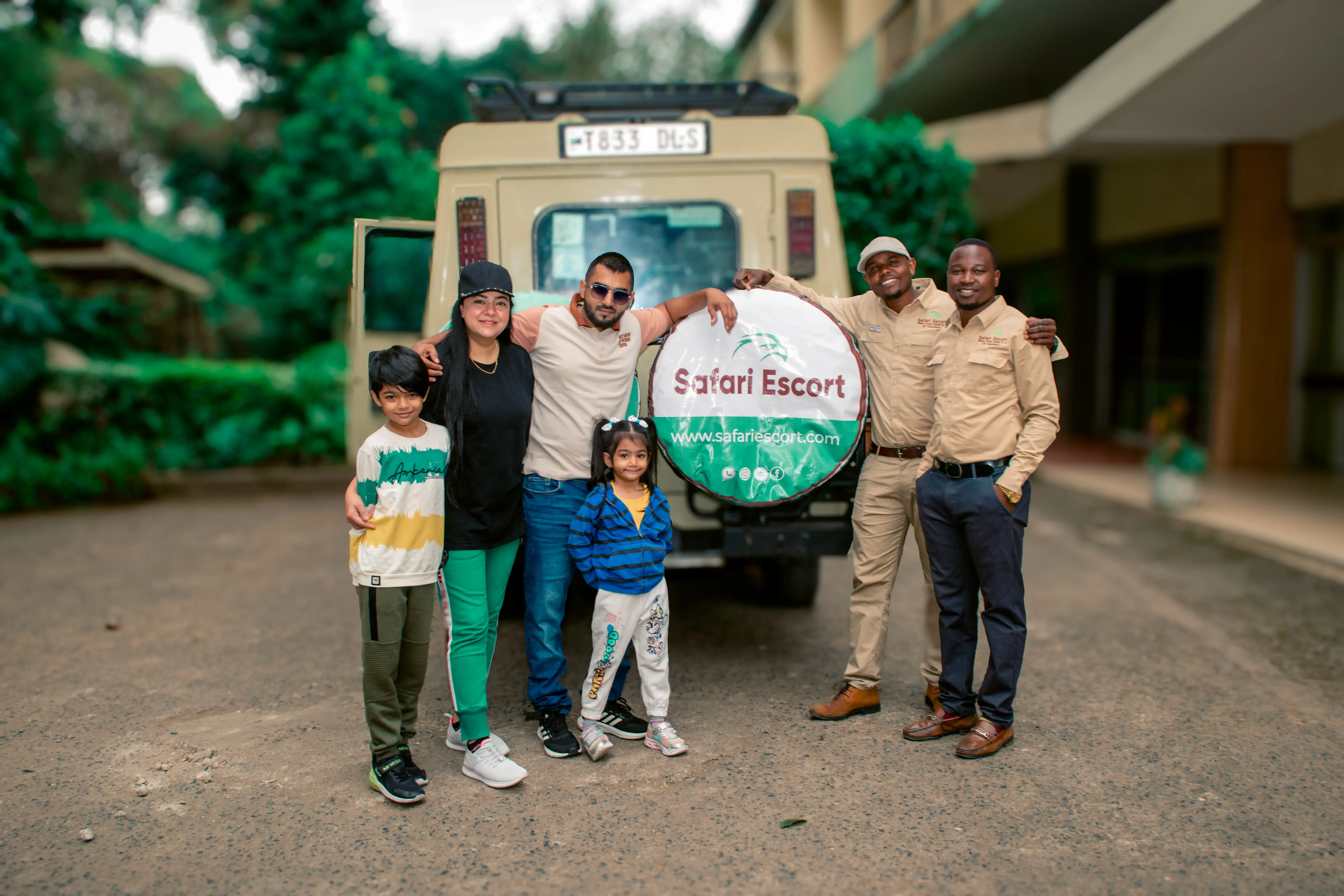 Safari Escort team welcoming guests beside a safari vehicle in Tanzania
