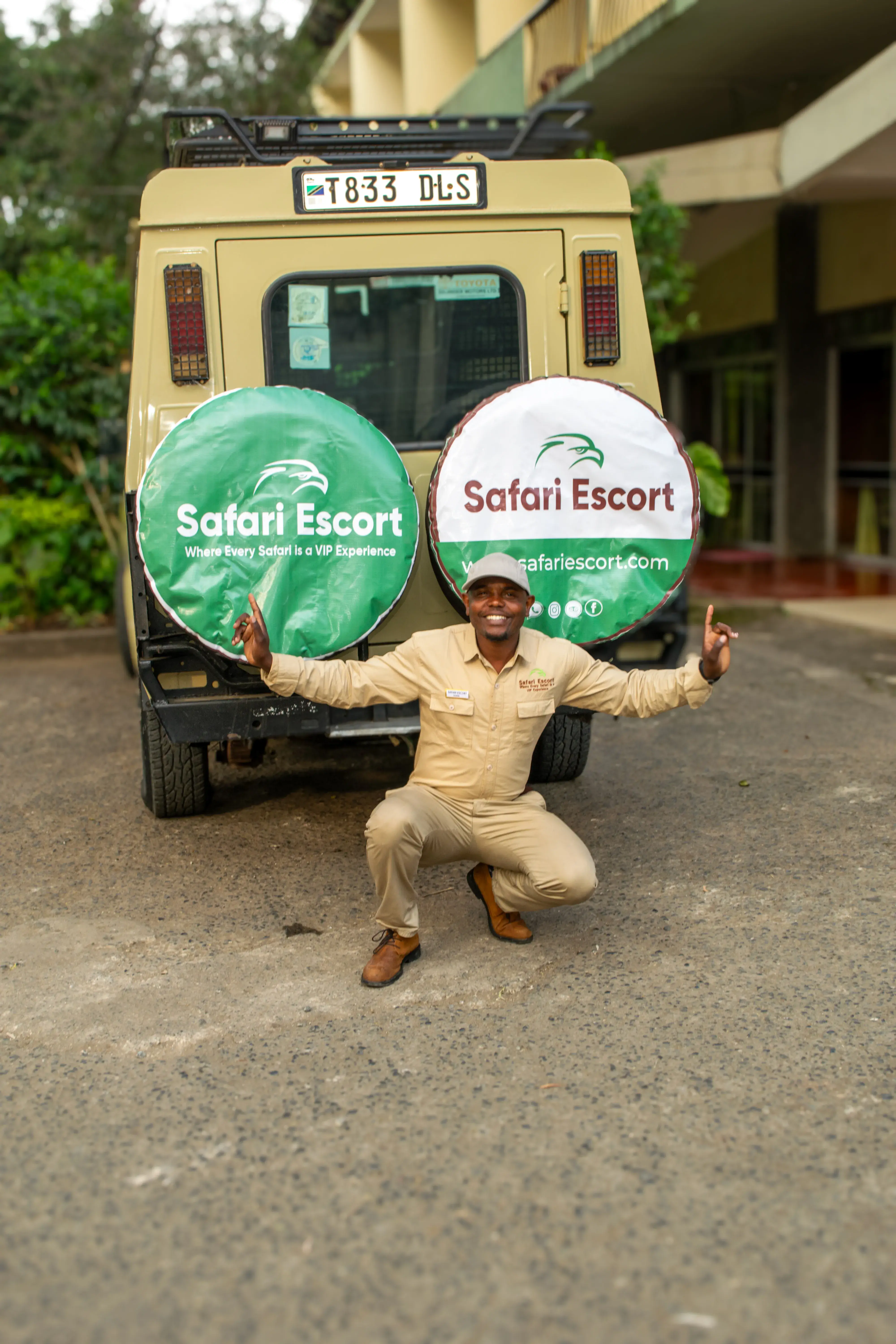 Safari Escort guide smiling beside a branded safari vehicle in Tanzania
